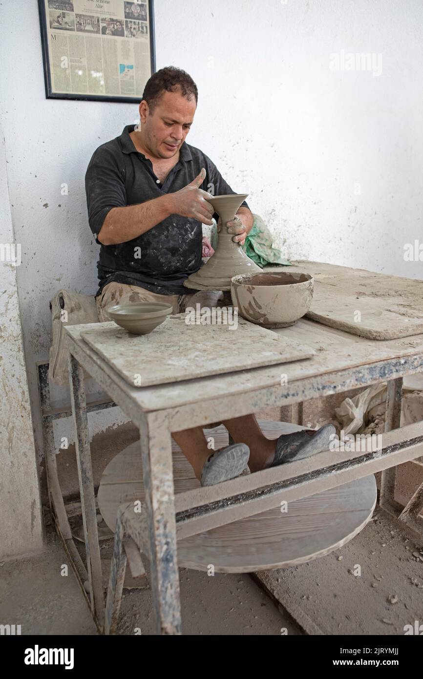 potier marocain à l'œuvre : tourner au panneau du potier et façonner les récipients en céramique et la poterie : cruches, assiettes dans l'atelier du potier, artisanat Banque D'Images