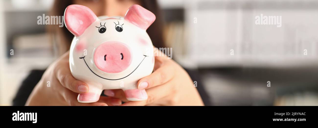 Jeune femme tenant une banque de porc dans les mains banque de porc rose. Accumulation de fonds concept Banque D'Images