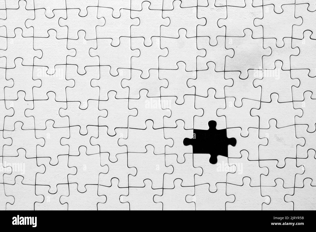 Fond noir montrant à travers la pièce manquante dans le puzzle blanc. Banque D'Images