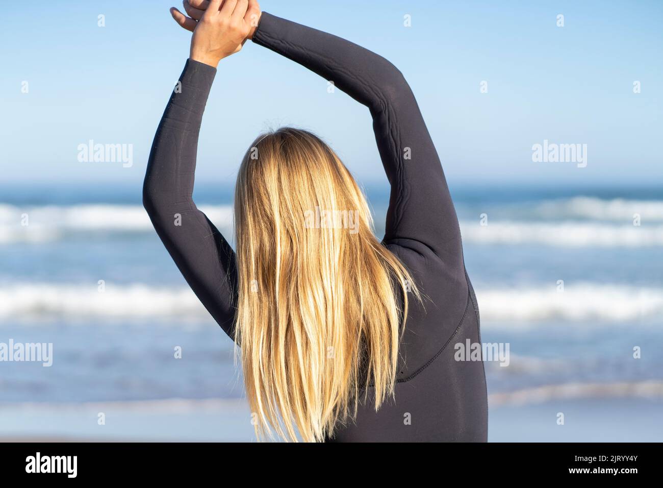 Surfeur se réchauffant à la plage le matin avant de surfer. Banque D'Images