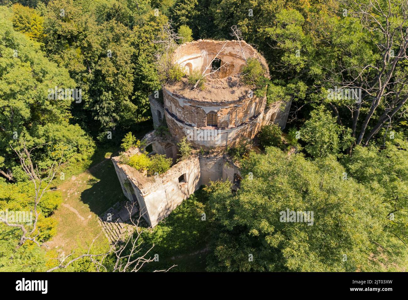 BirdsEye vue de l'extérieur de l'église abandonnée endommagée avec tour sans toit au milieu de la forêt verdoyante. Ruines de vieux temple. Tir horizontal. Photo de haute qualité Banque D'Images