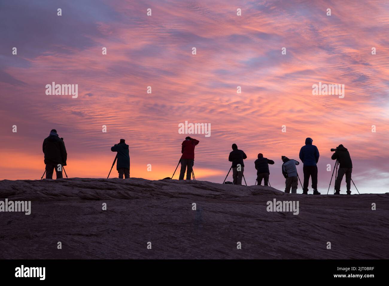 Silhouette d'un groupe de photographes dans un atelier photo prenant des photos au lever du soleil près de Moab, Utah. Banque D'Images