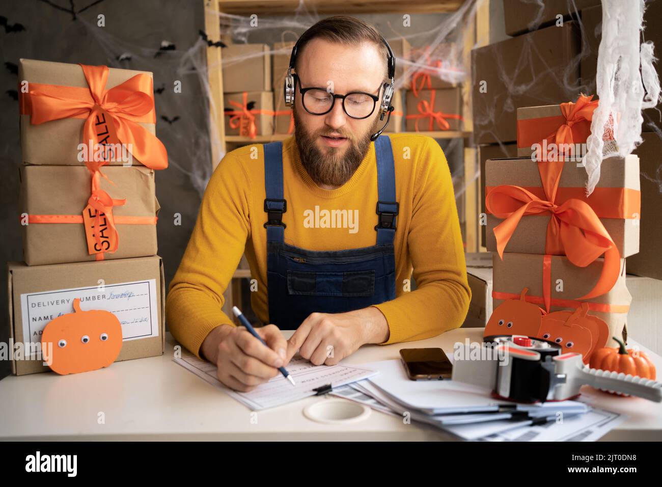Un propriétaire de petite entreprise de dropping masculin utilisant un casque. Employé d'entrepôt, vendeur. Grande vente de produits rabais et promotions de Halloween. Banque D'Images