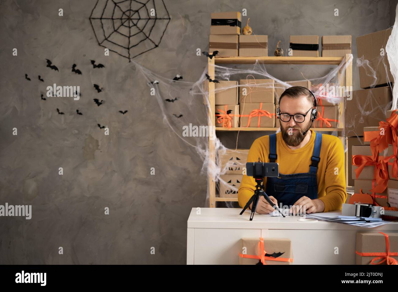 Un homme dropshipping propriétaire de petite entreprise en utilisant un téléphone. Employé d'entrepôt, vendeur. Grande vente de rabais et de promotions de biens en l'honneur de Halloween. Banque D'Images