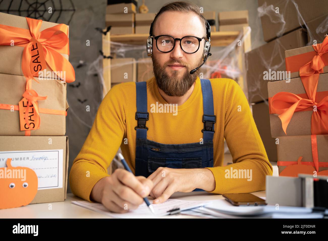 Un propriétaire de petite entreprise de dropping masculin utilisant un casque. Employé d'entrepôt, vendeur. Grande vente de produits rabais et promotions de Halloween. Banque D'Images