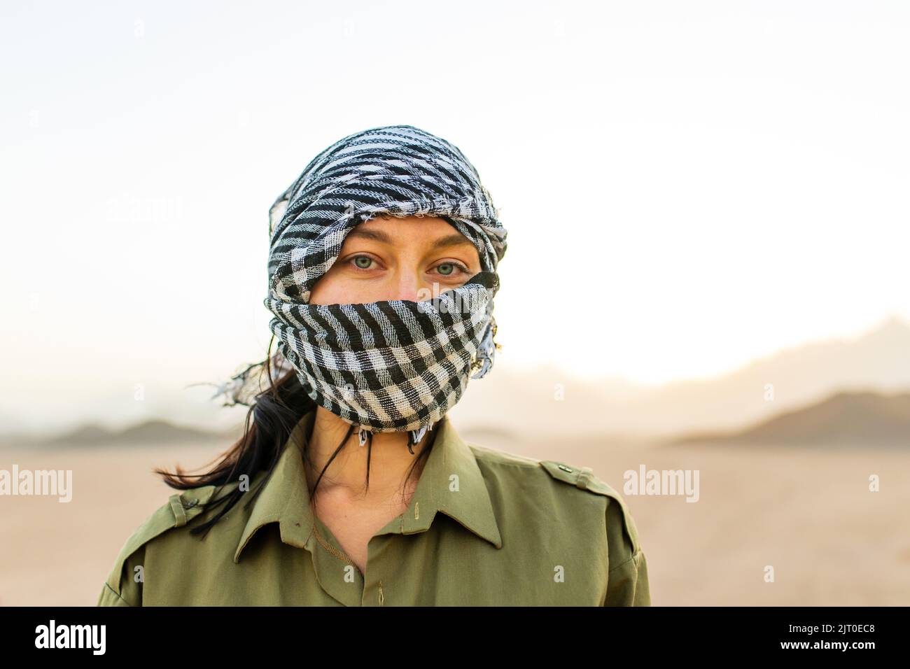 femme avec tête et visage couverts avec foulard à carreaux noir et blanc sur fond désertique Banque D'Images