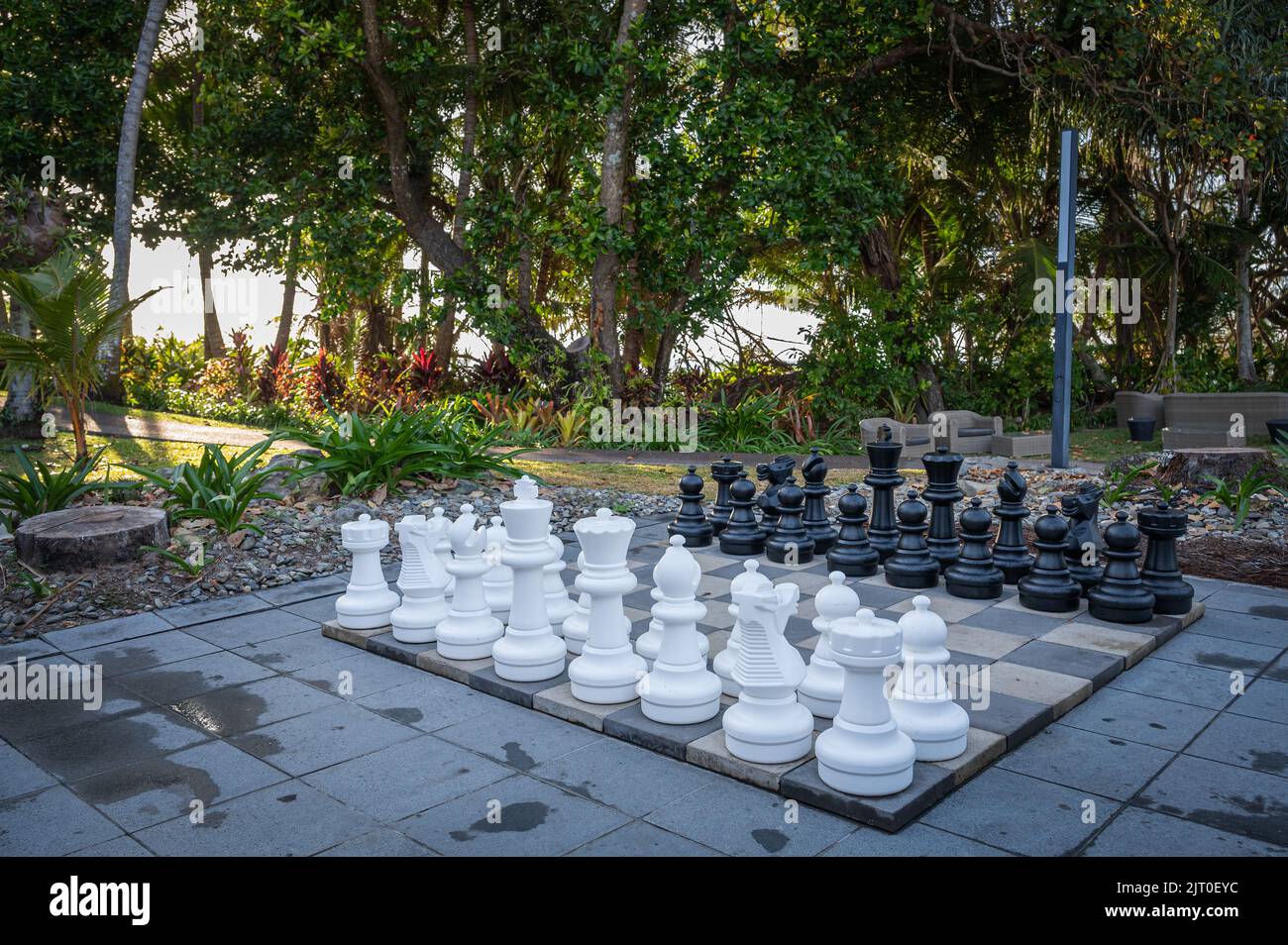 Une retraite dans un jardin tropical magnifiquement organisé, avec un jeu d'échecs géant, des meubles de jardin sur une plage de 4 kilomètres de Port Douglas, Queensland, Australie. Banque D'Images