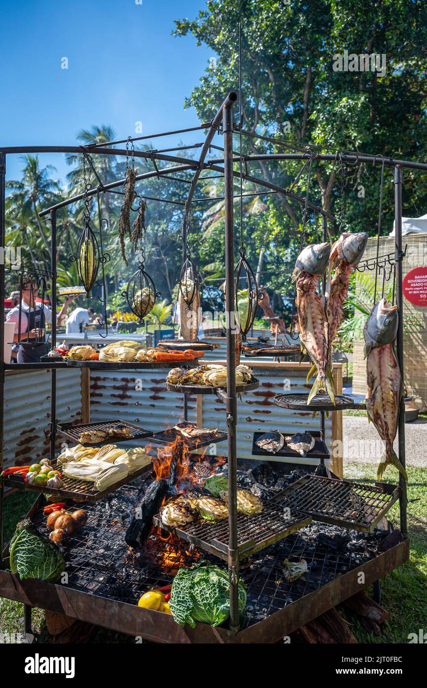 Structure de barbecue élaborée au premier plan torréfaction de la cuisine somptueuse pendant que le serveur livre des boissons à un festival à Port Douglas, Queensland, Australie. Banque D'Images