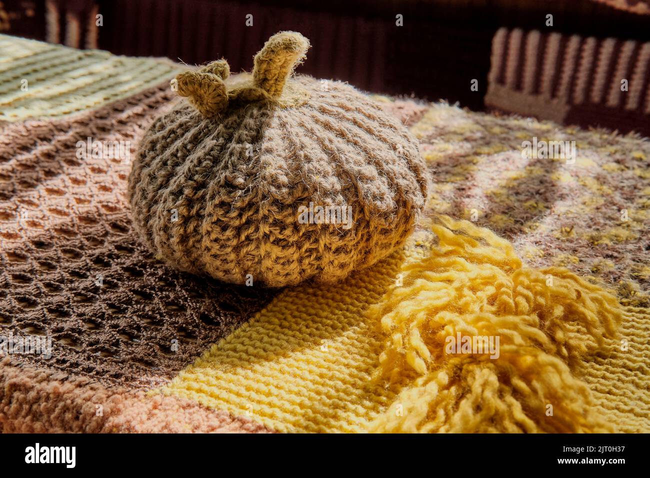 Potiron en laine beige tricoté sur la table recouvert d'une nappe en patchwork tricotée. Décoration d'intérieur Banque D'Images