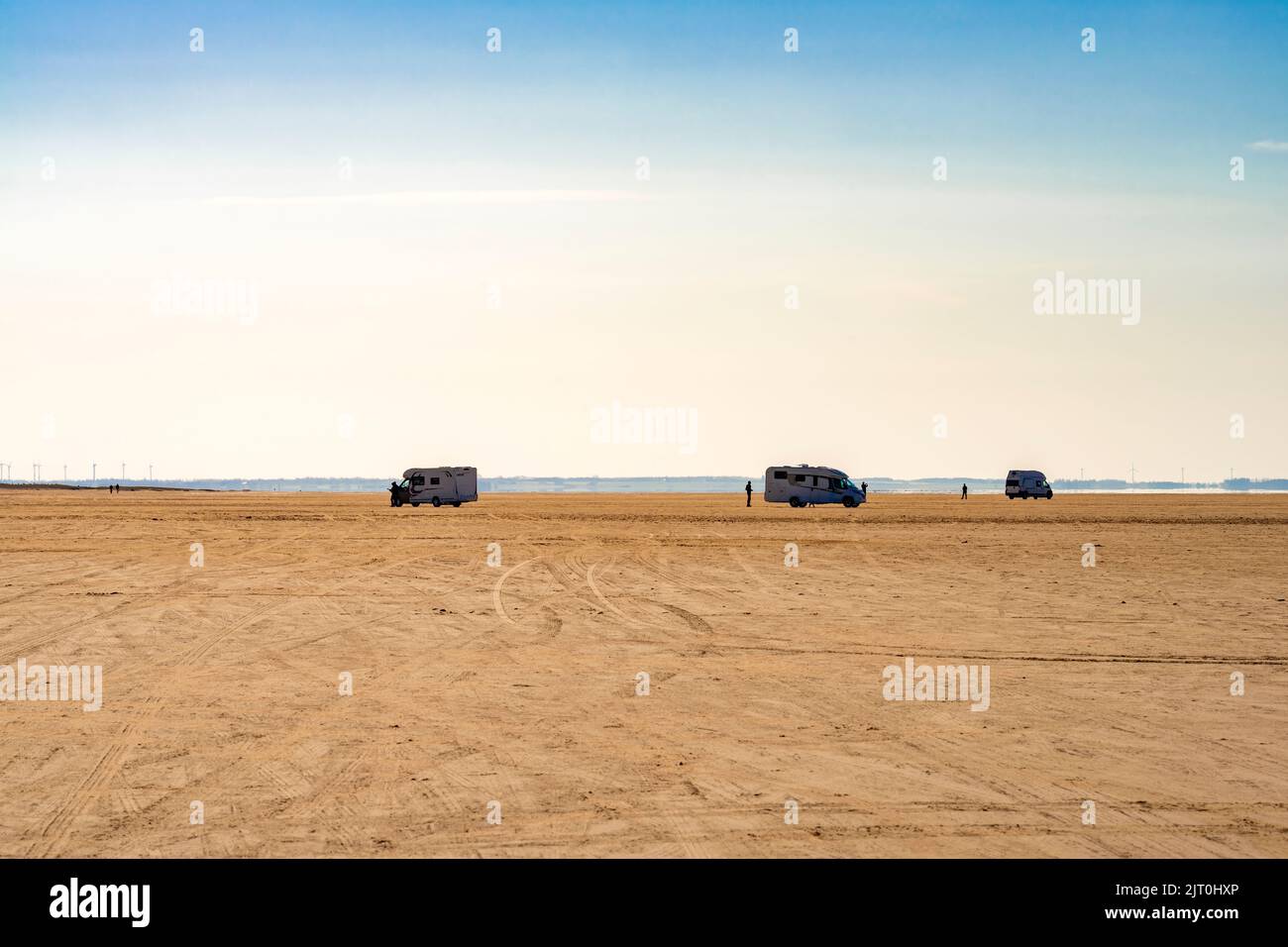 Trois véhicules de camping entourés par des personnes en arrière-plan d'une plage Banque D'Images