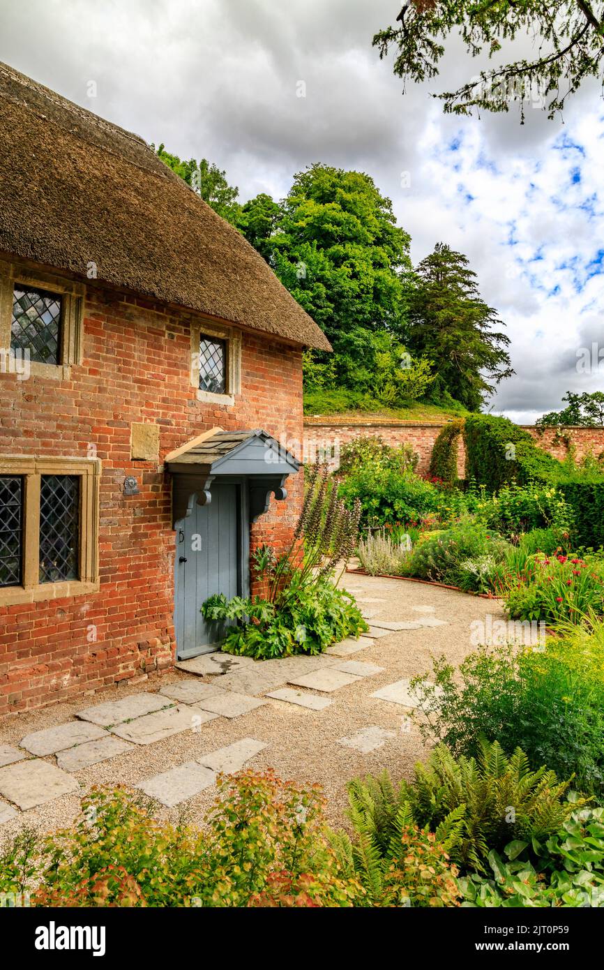 Le traditionnel cottage en briques rouges au toit de chaume dans le jardin du Cottage Garden, dans le jardin et l'hôtel restauré 'The Newt in Somerset', nr Bruton, Angleterre, Royaume-Uni Banque D'Images