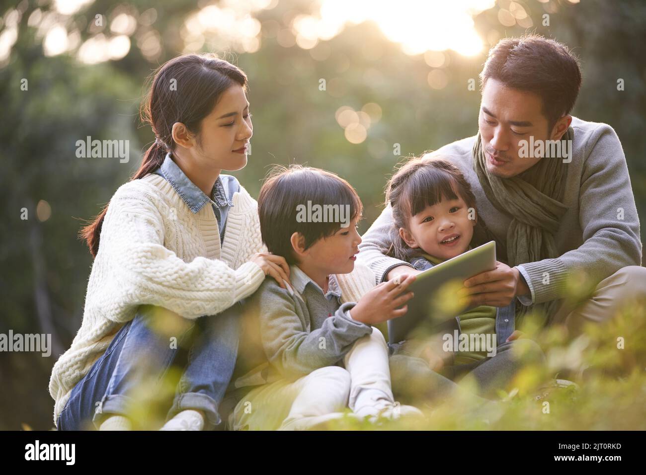 famille asiatique avec deux enfants se détendant à l'extérieur dans le parc de la ville Banque D'Images