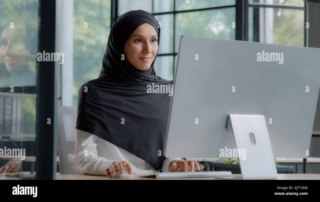 Confiante réussie élégante femme d'affaires arabe dactylographiant sur ordinateur attirante femme musulmane dans hijab travailleur professionnel cadre expérimenté Banque D'Images