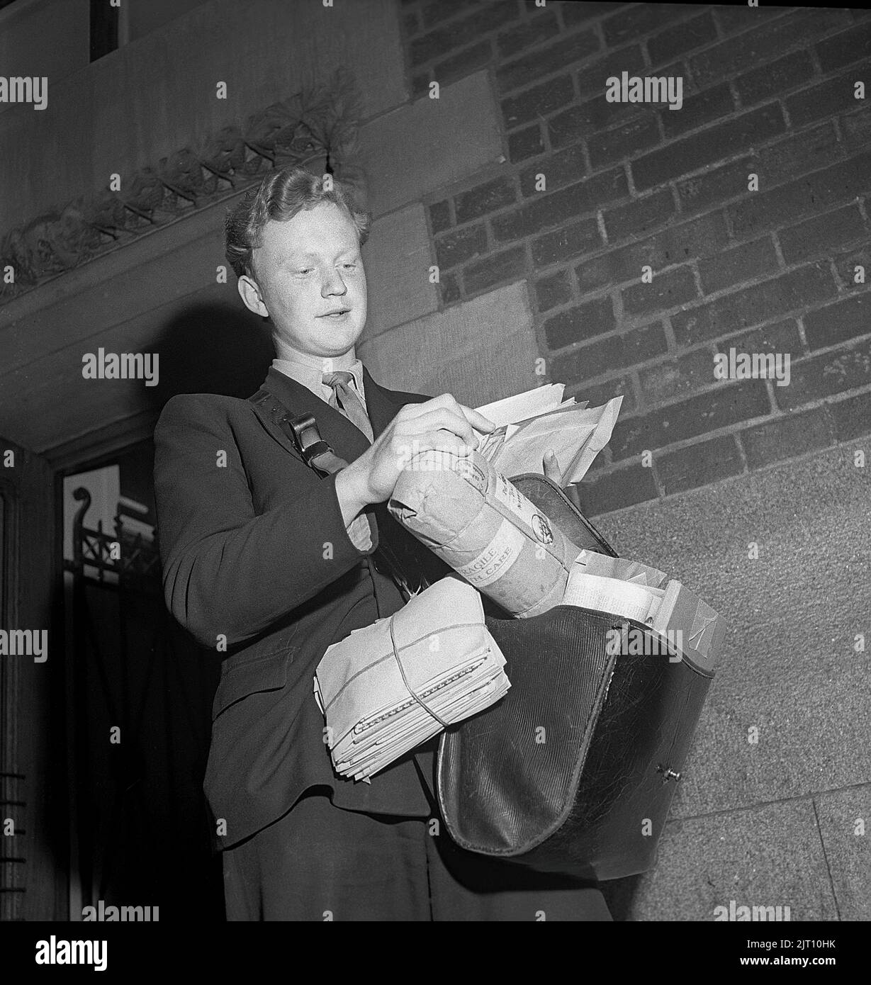 1940s mailman. Le poste est prêt à être livré et le jeune mailman a son sac plein de lettres et de colis. Angleterre 1946 Kristoffersson U94-1 Banque D'Images