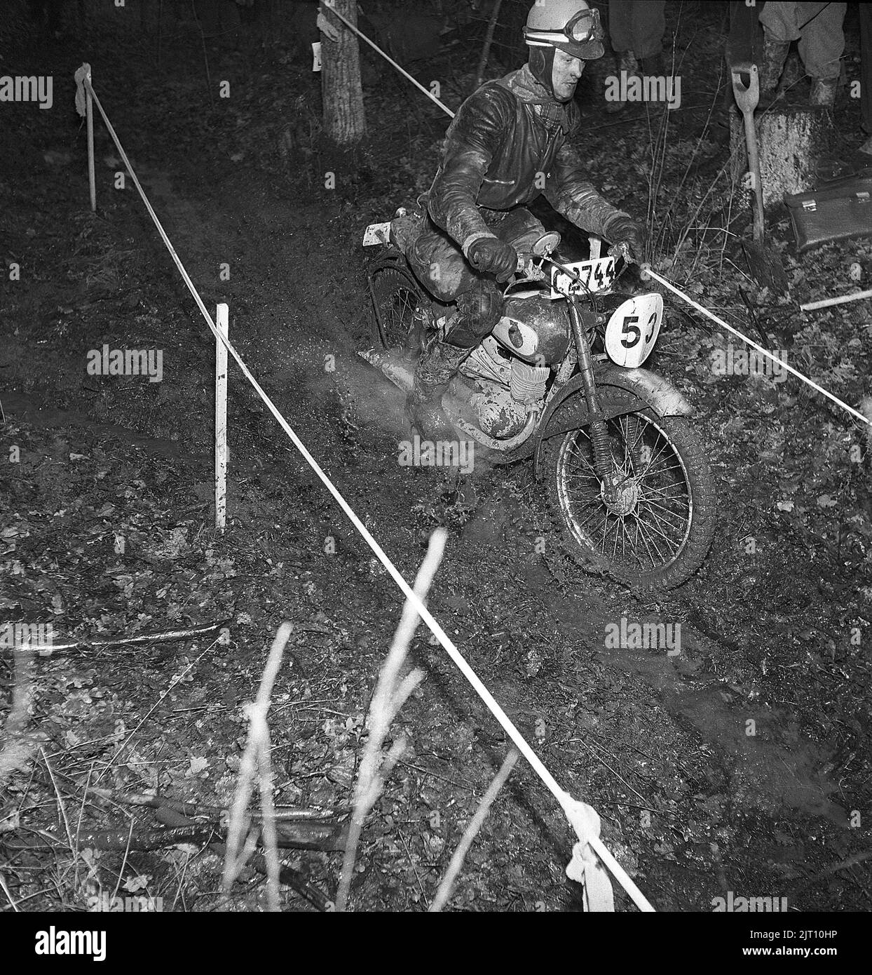 Motocycliste en 1950s. Un homme portant sur sa moto pendant une course de nuit où la piste est dans la nature avec de la boue et de l'eau. Suède 1951 Kristoffersson réf. BE73-1 Banque D'Images
