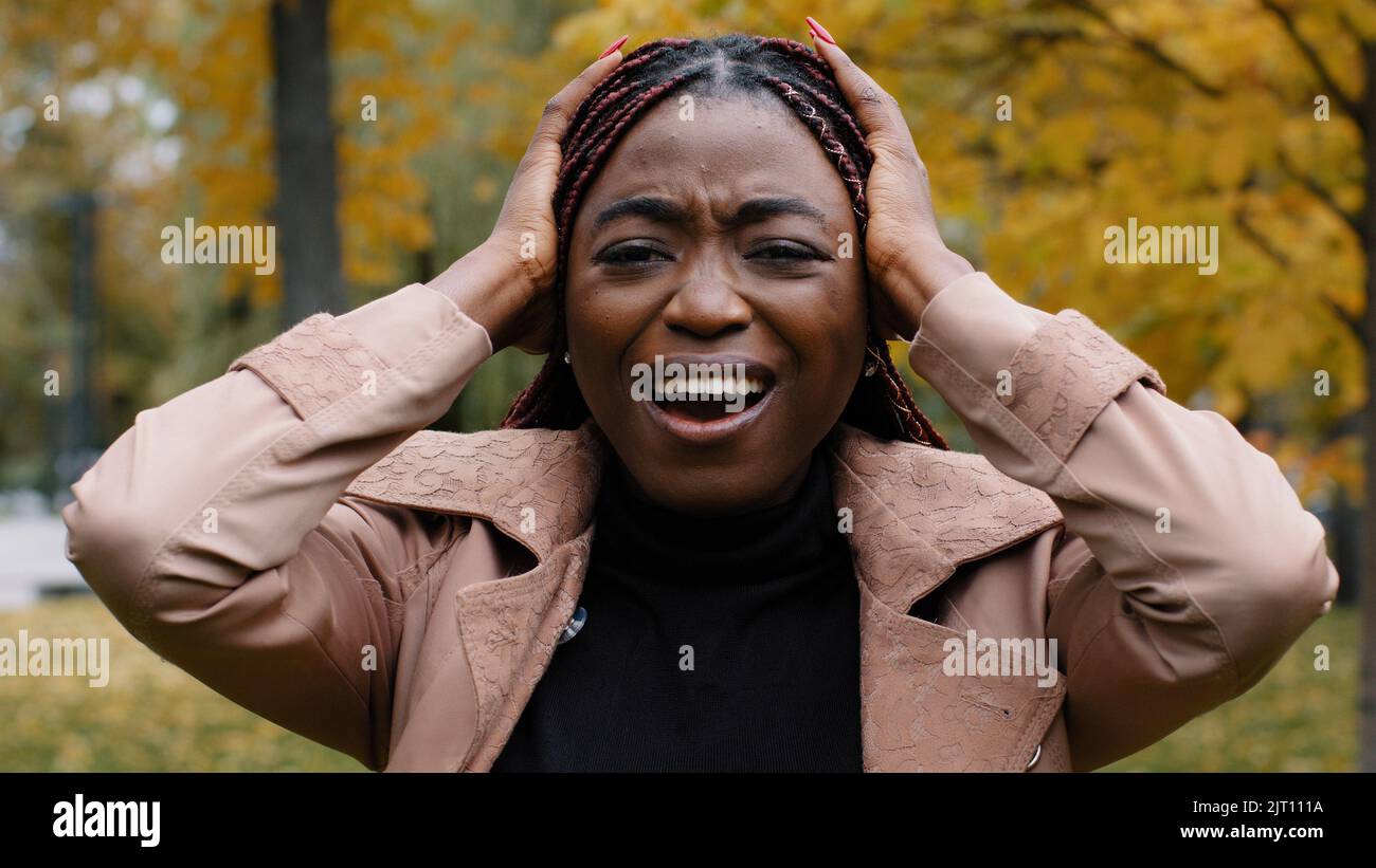 Gros plan inquiète inquiète anxiété jeune femme debout à l'extérieur criant bruyamment dans la rage couvre les oreilles avec les paumes du bruit agacé la fille frustrée ressent le stress Banque D'Images