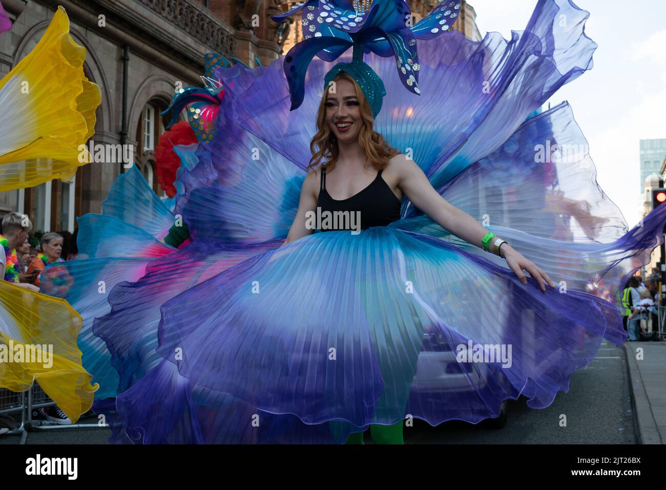 Défilé de la fierté de Manchester. Femme en costume de fleur bleu. Thème Marche pour la paix. Banque D'Images