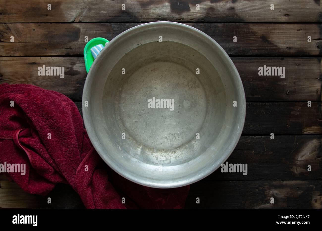 un bol en aluminium avec de l'eau savonneuse après le lavage de vos pieds est sur le sol à côté de savon et une serviette, un bol d'eau sur le sol, laver dans un bol Banque D'Images