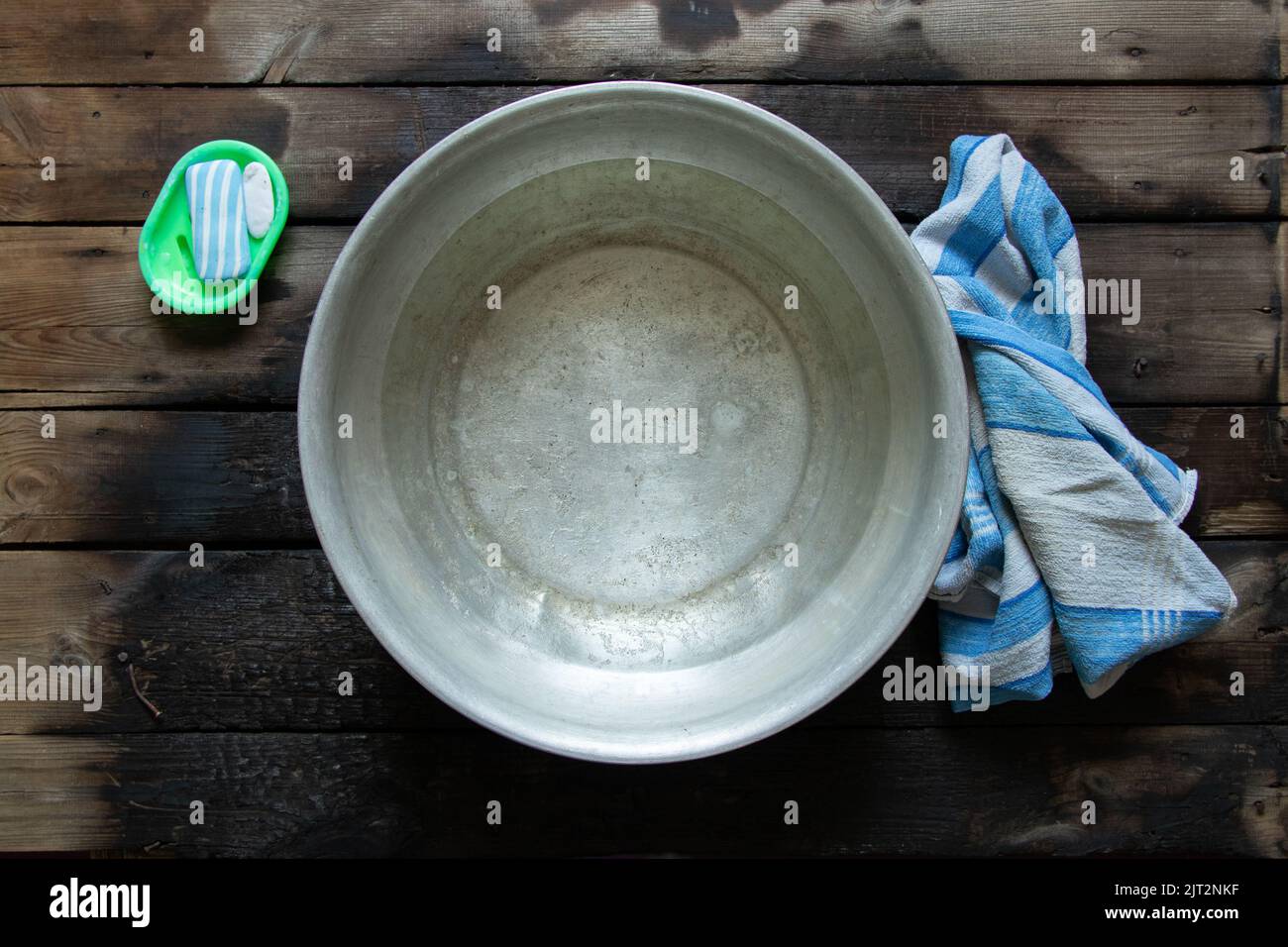 un bol en aluminium avec de l'eau savonneuse après le lavage de vos pieds est sur le sol à côté de savon et une serviette, un bol d'eau sur le sol, laver dans un bol Banque D'Images