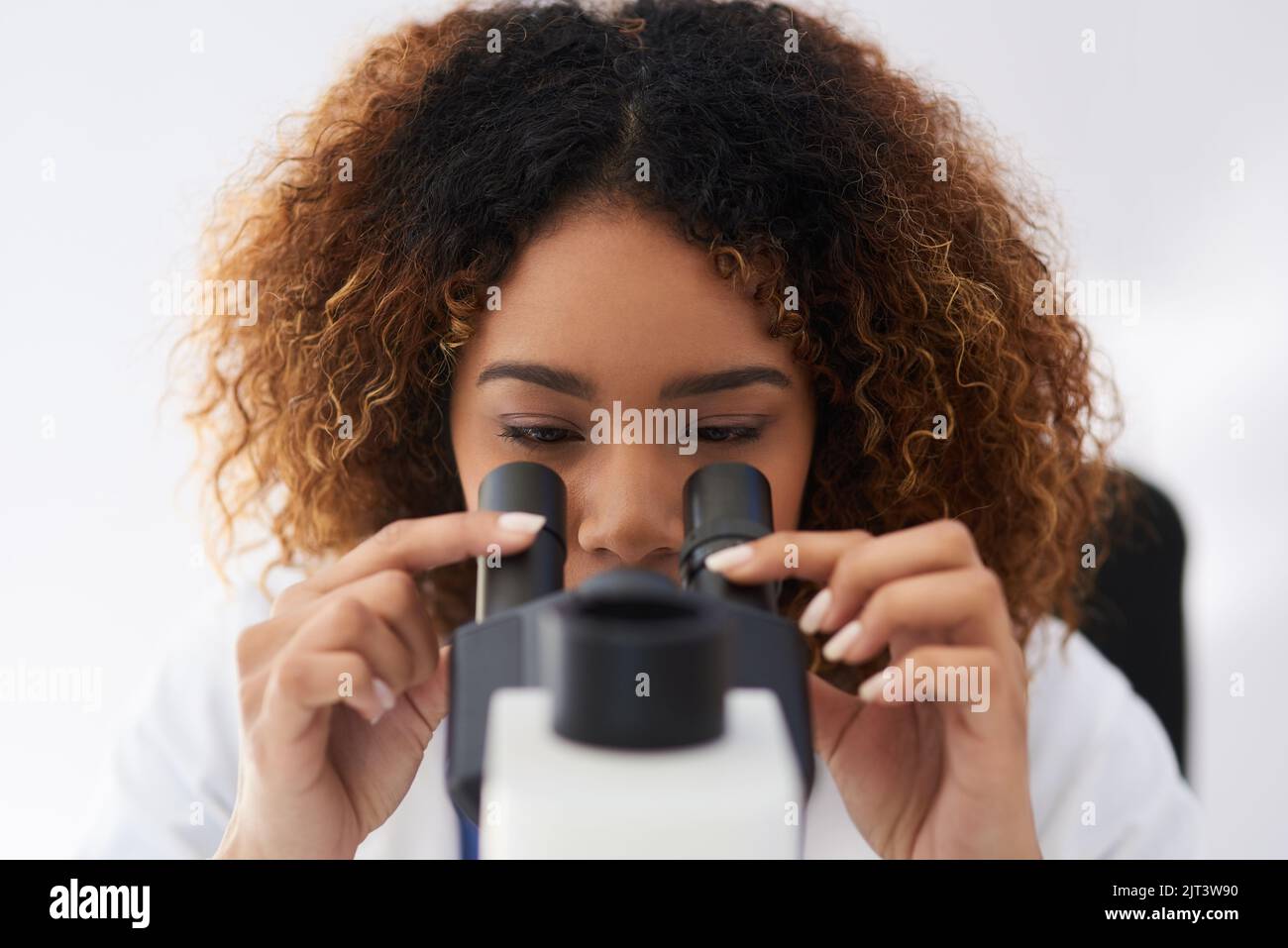 Une jeune scientifique qui cherche un microscope. Banque D'Images