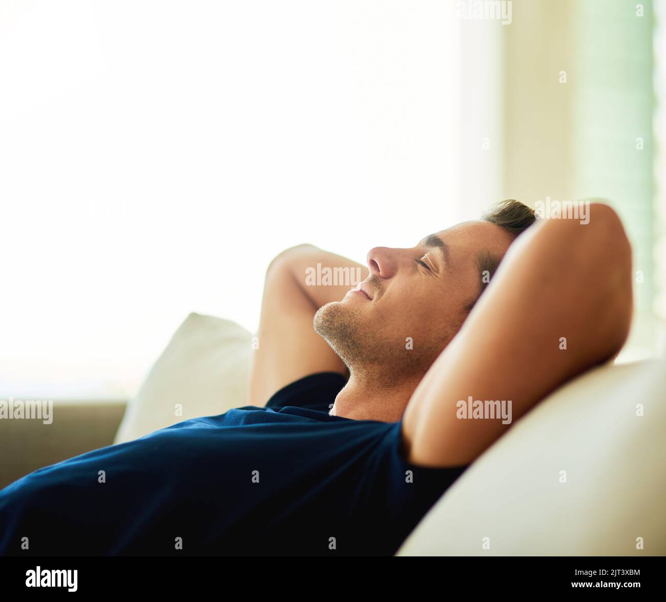 Un beau jeune homme qui se repose sur son canapé à la maison. Banque D'Images