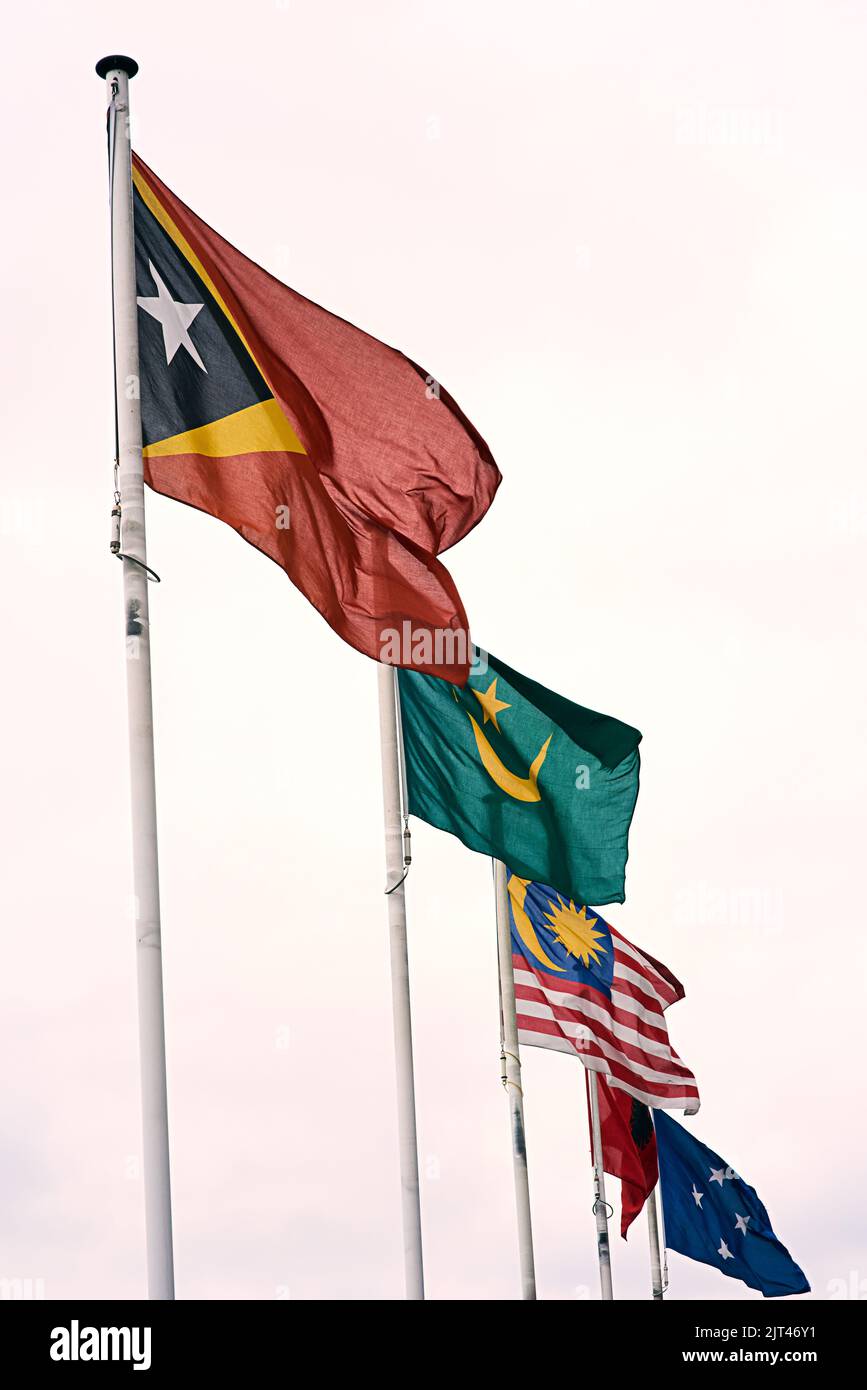 Vol sur une seule ligne. Les drapeaux du Timor oriental, de la Mauritanie, de la Russie et des États fédérés de Micronésie soufflent dans le vent. Banque D'Images
