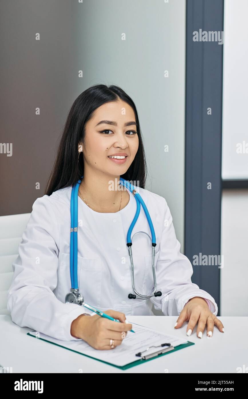 Portrait d'une femme généraliste asiatique vêtue d'un manteau blanc assise sur son lieu de travail à la clinique médicale. la consultation médicale Banque D'Images