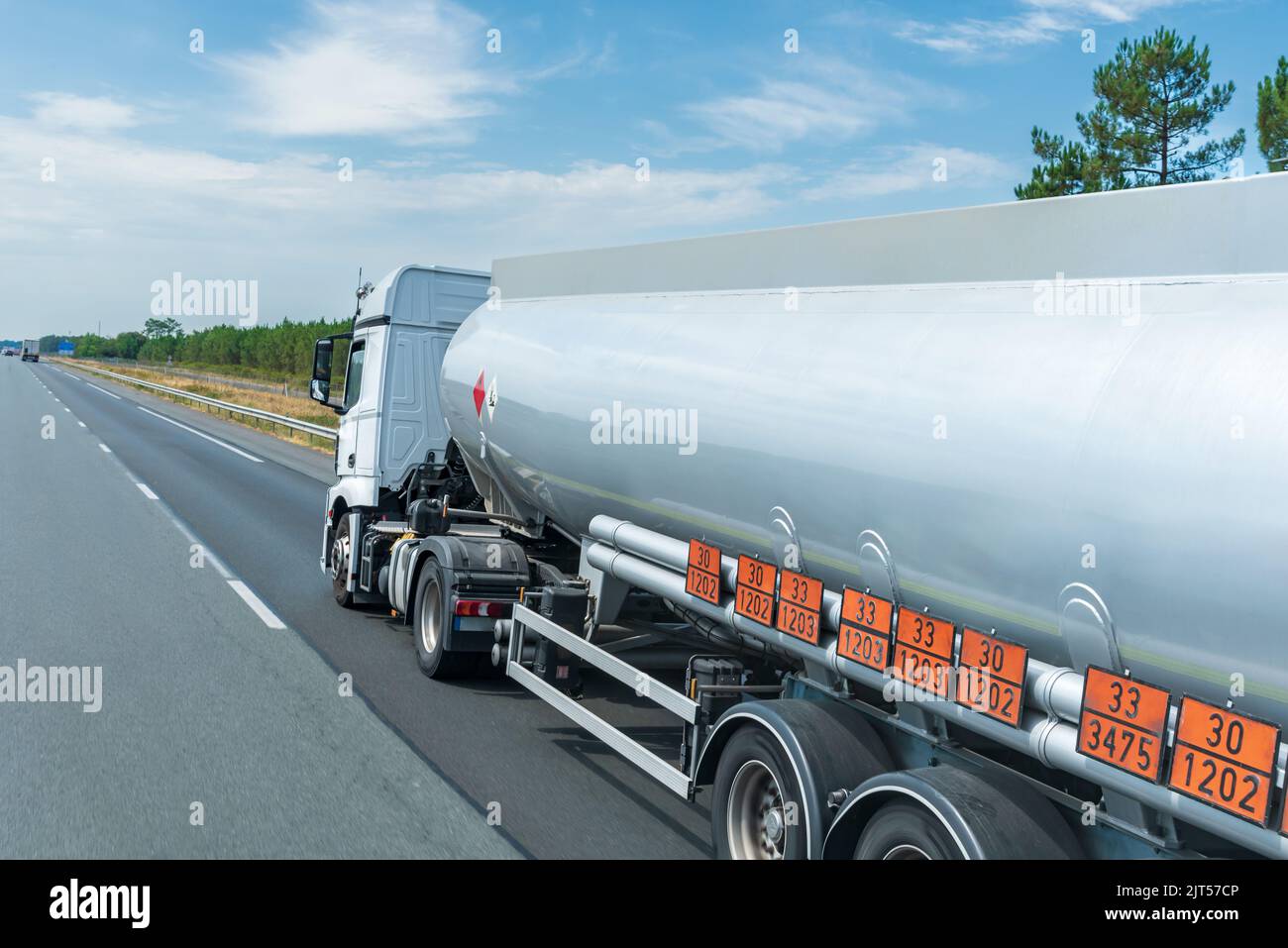 Camion-citerne à carburant circulant sur la route avec des panneaux orange identifiant le danger et la marchandise transportée. Banque D'Images