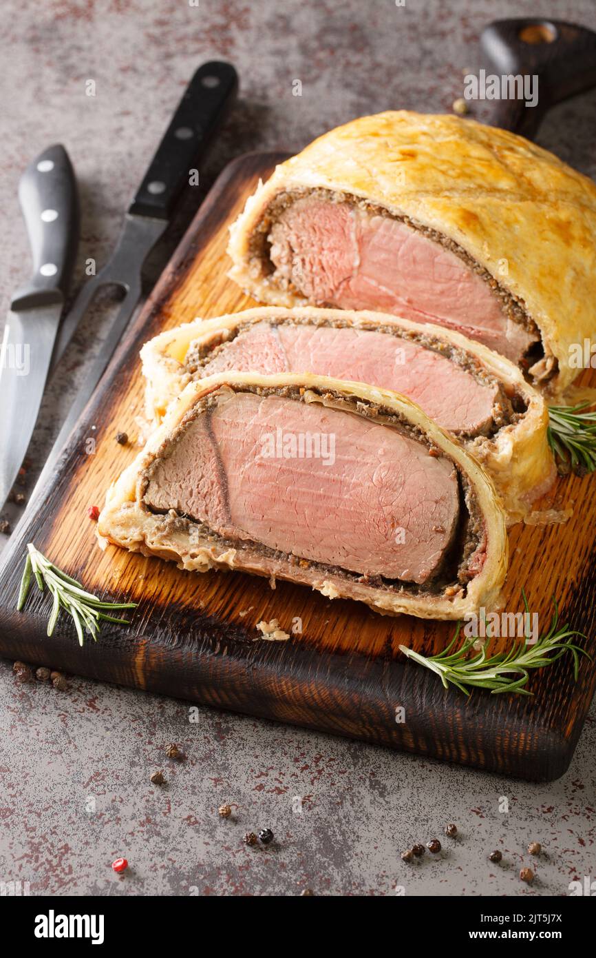 Viande de bœuf à angle élevé cuisson wellington ou bœuf en morceaux coupé en tranches sur fond gris de planche à découper. Verticale Banque D'Images