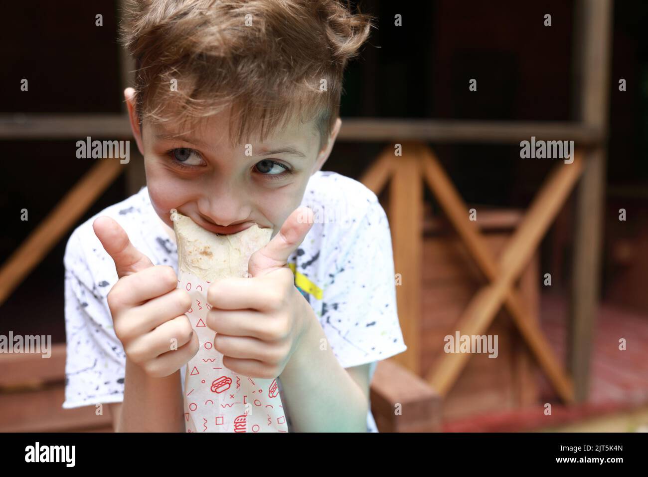 Un garçon affamé mangeant du shawarma sur la terrasse du restaurant Banque D'Images