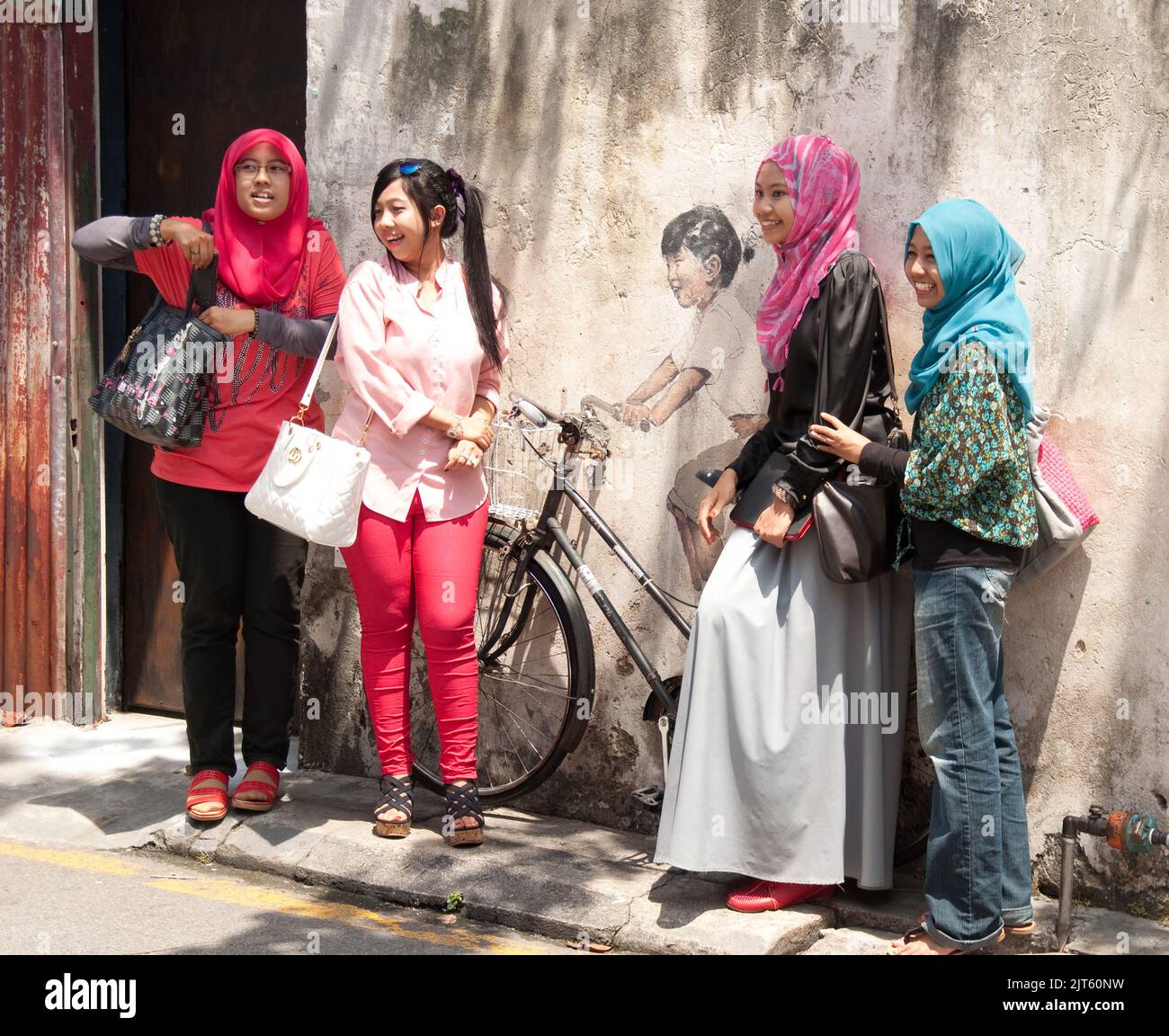 Posant autour de Street Art, George Town, Penang, Malaisie, Asie. Les jeunes femmes musulmanes s'amusent et s'amusent. L'art de la rue est très commun en G. Banque D'Images