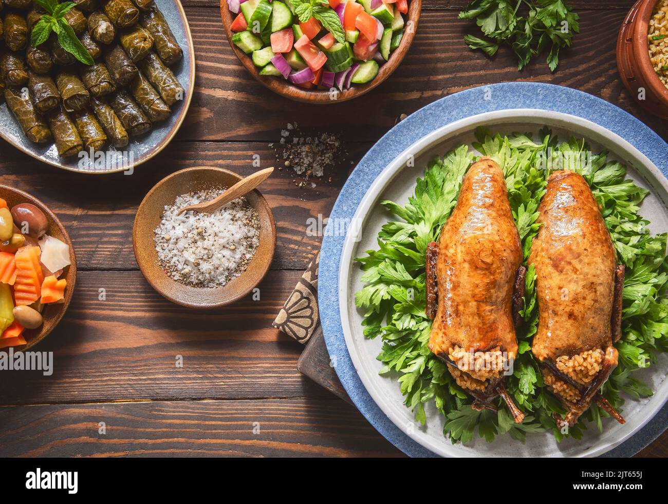 Cuisine arabe ; pigeon traditionnel égyptien farci ou plat « Hamam Mahshi ». Servi avec une salade verte, des cornichons orientaux, des feuilles de vigne et du Freekeh cuit. Banque D'Images