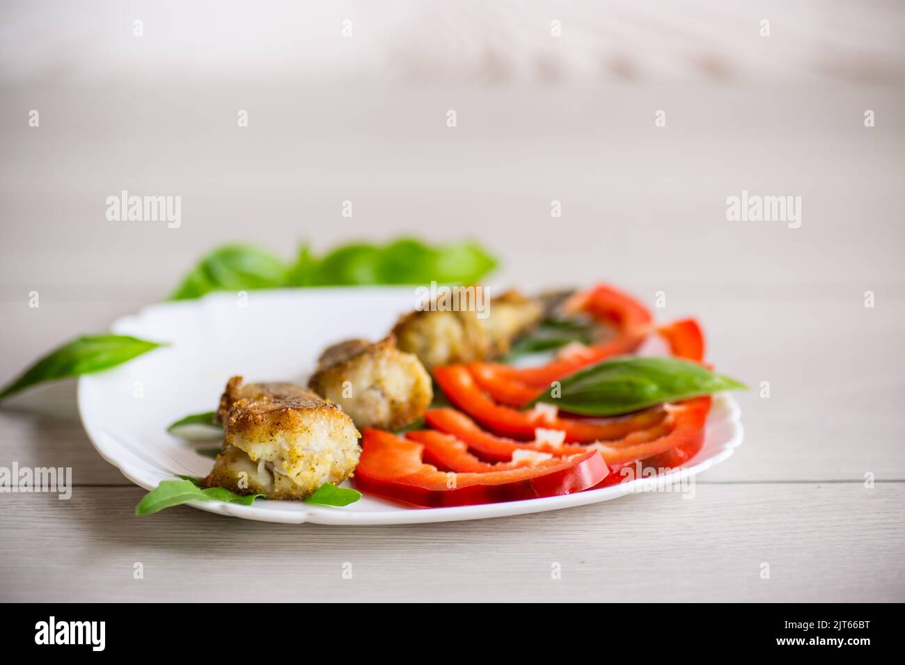Morceaux de merlu frits dans une assiette de poivre sur une table en bois Banque D'Images