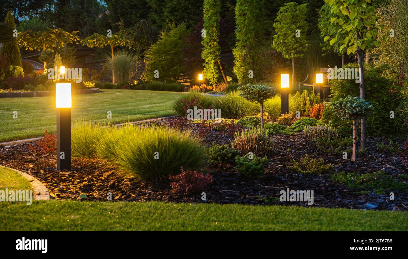 Photo panoramique des bornes lumineuses LED illuminées jardin de l'arrière-cour pendant les heures de nuit. Systèmes d'éclairage extérieur d'arrière-cour modernes. Banque D'Images