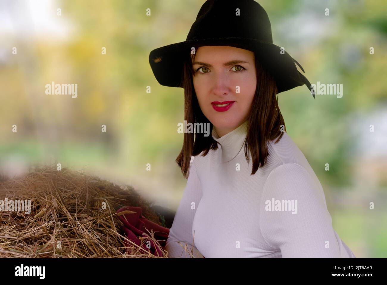 une femme souriante dans un chapeau de cow-boy. Femme avec un chapeau sur un ranch. Agriculteur d'âge moyen. Arrière-plan flou de la nature Banque D'Images