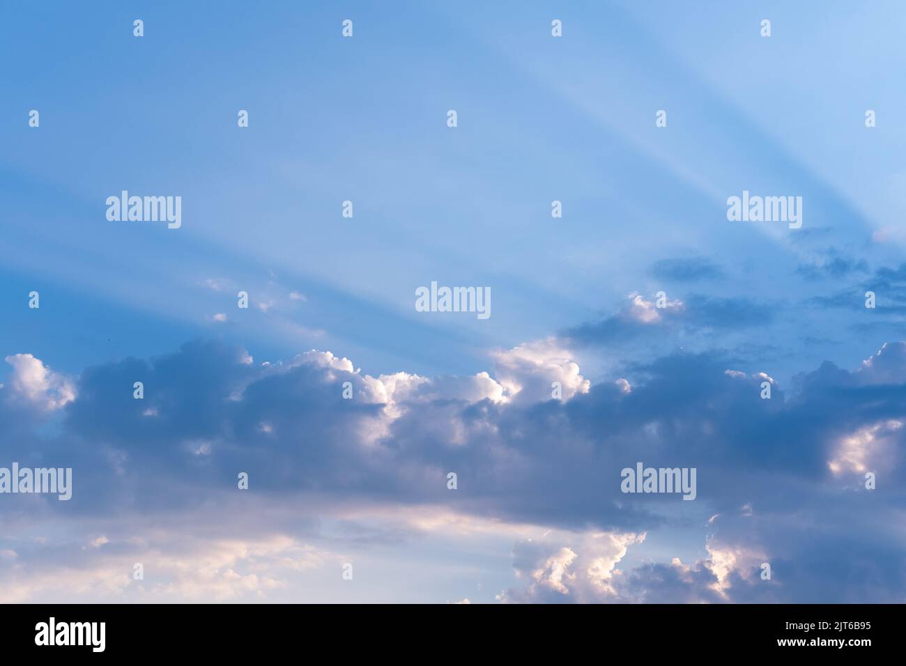 Ciel nocturne avec des nuages éclairés, coucher de soleil incroyable et lumière du soleil majestueuse qui se brisent à travers les nuages et laissant des traînées de rayons sur le fond de Banque D'Images