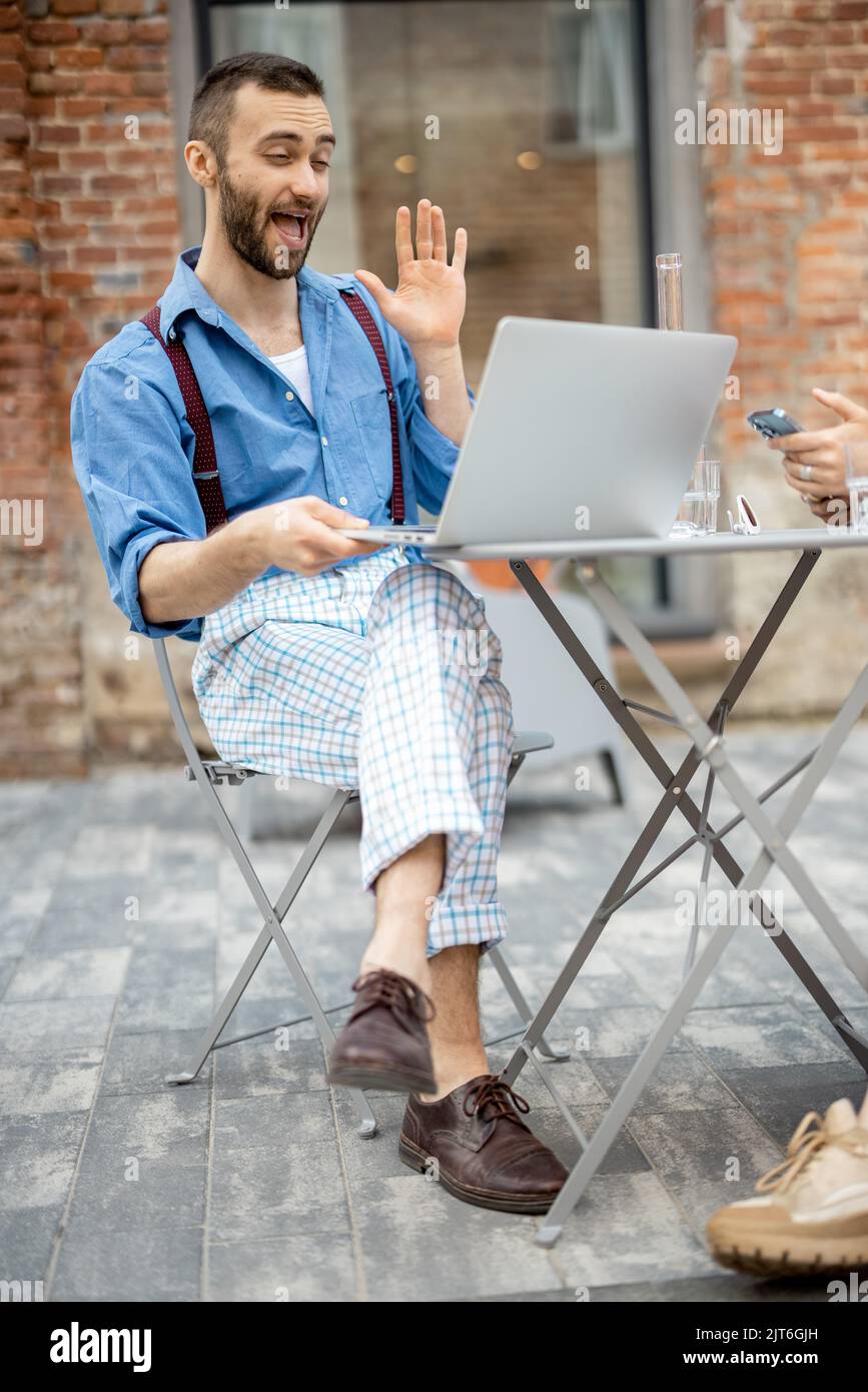 Un homme d'affaires élégant a une conversation en ligne sur ordinateur portable au café Banque D'Images