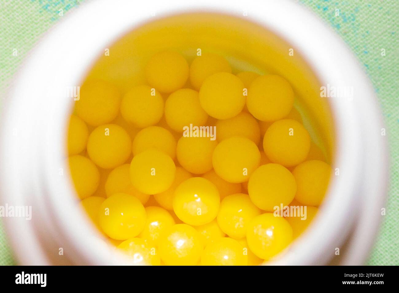 Poignée de capsules de vitamine c jaune pour la santé dans un petit pot blanc. Banque D'Images