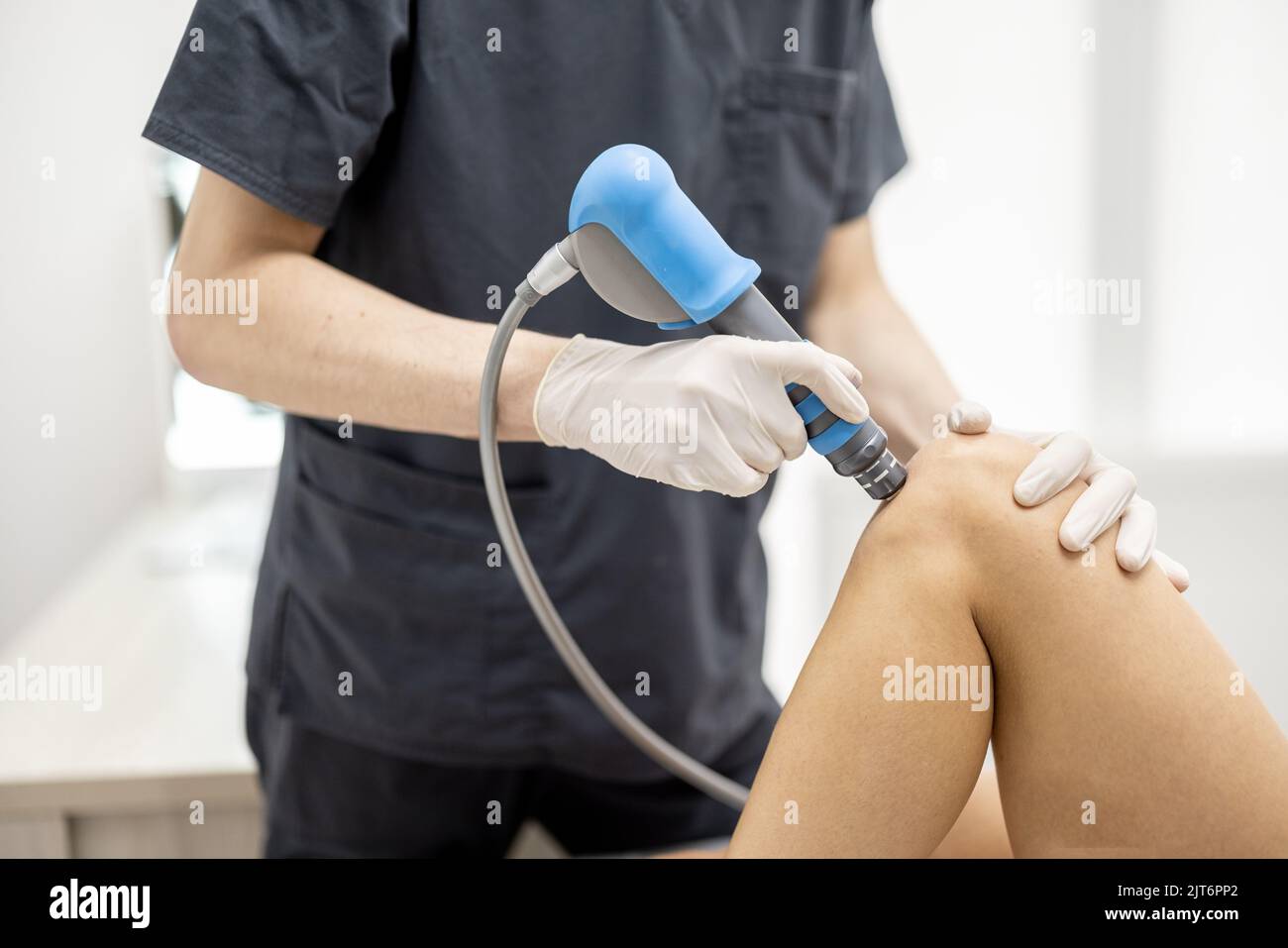 Le médecin applique un traitement par onde de choc sur le genou des femmes Banque D'Images