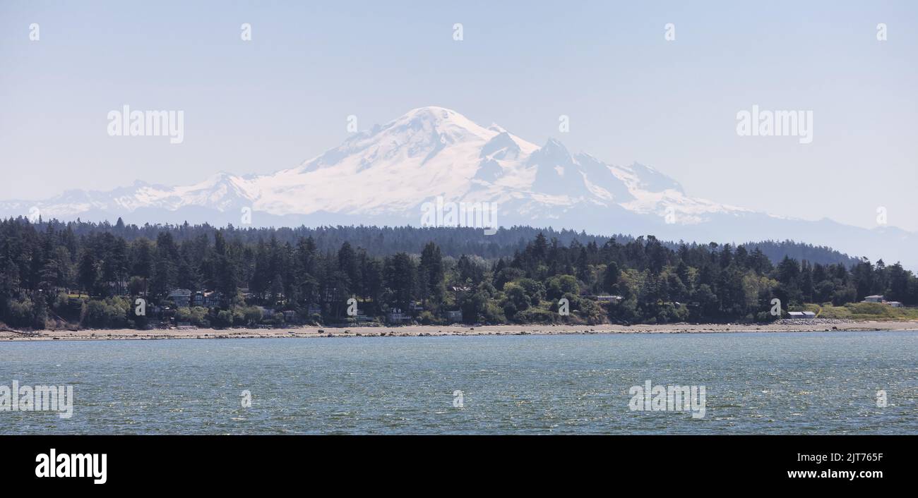 Maisons au bord de la plage sur la côte ouest de l'océan Pacifique avec montagne enneigée Banque D'Images