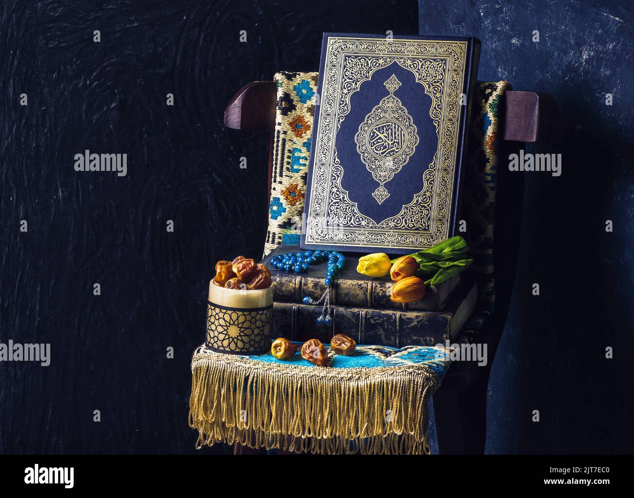 Le Saint-Livre islamique 'Coran' est placé avec des perles roses de tulipe, des dates fraîches et un tapis de prière sur une chaise en bois. Banque D'Images
