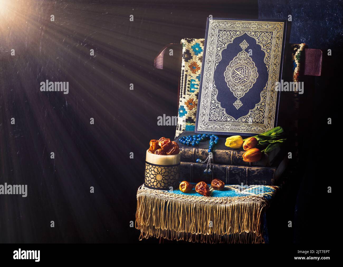 Le Saint-Livre islamique 'Coran' entouré de rayons lumineux et placé avec des perles rosaires, des dattes fraîches, des fleurs de tulipe et un tapis de prière sur une chaise en bois. Banque D'Images