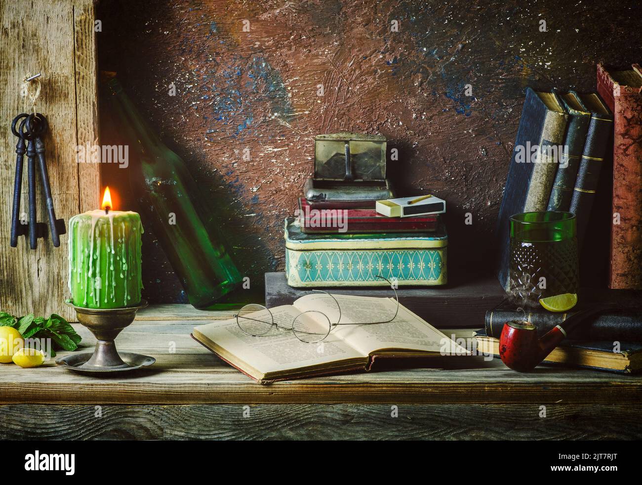 Classique encore la vie avec des livres vintage placés avec une bougie éclairée, de vieilles boîtes, pipe, clés anciennes, citron, menthe et boisson sur fond rustique en bois. Banque D'Images
