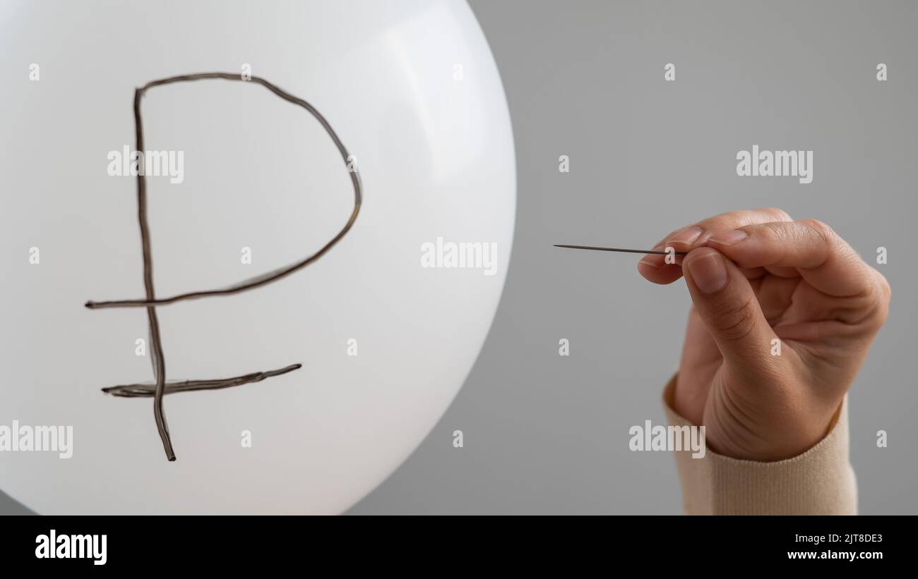 Une femme caucasienne fait apparaître un ballon avec une inscription rouble et une aiguille. Banque D'Images