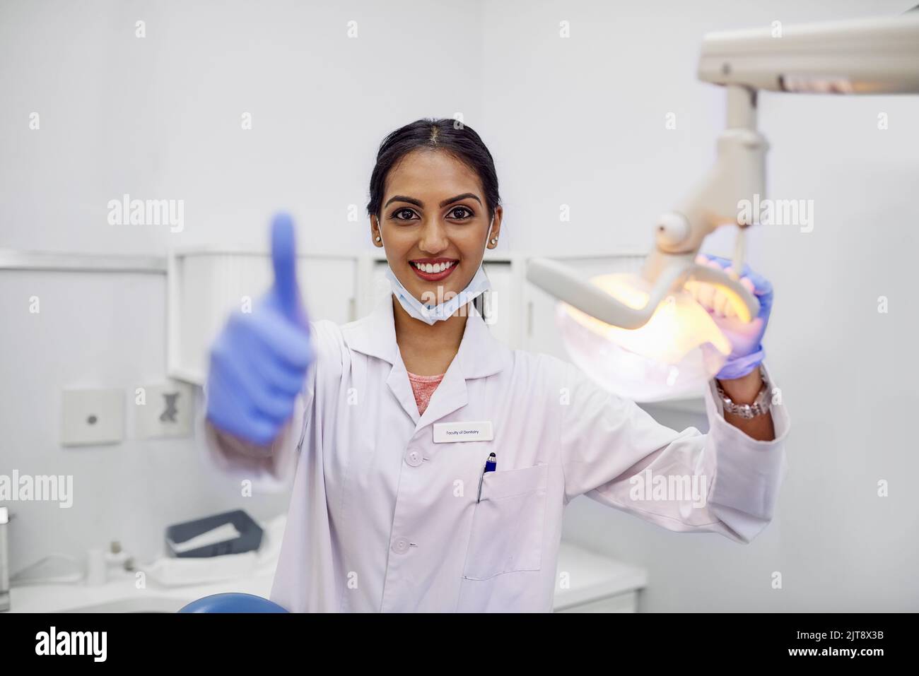 Ici pour vous aider à maintenir une bonne santé bucco-dentaire. Portrait d'une jeune femme dentiste montrant les pouces dans son bureau. Banque D'Images