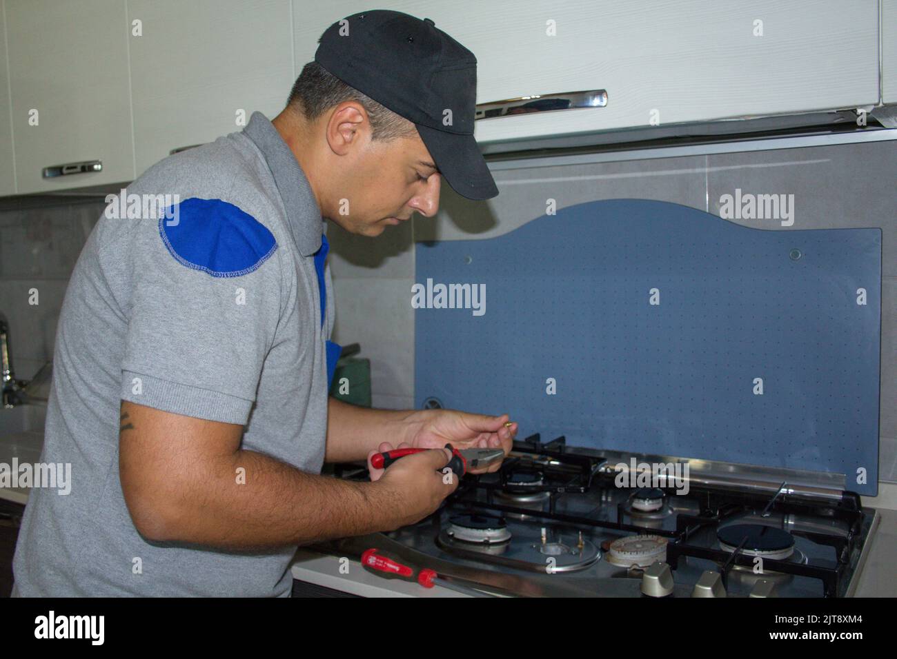 Image d'un homme de main qui répare la plaque de cuisson dans une cuisine maison. Problème avec les cuisinières à gaz Banque D'Images