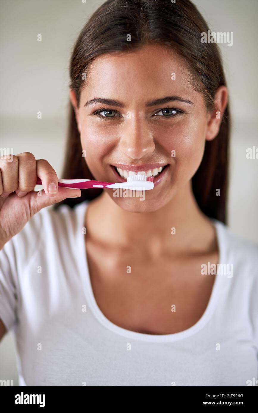Shes a investi dans une bonne santé bucco-dentaire. Portrait d'une belle femme se brossant les dents dans la salle de bains à la maison. Banque D'Images