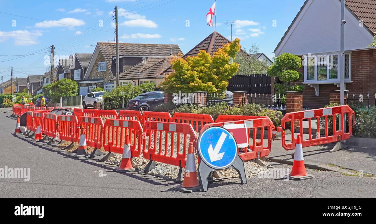 Infrastructure rurale à large bande travaux routiers signe de rue temporaire cônes et barrière de sécurité en plastique rouge emboîtable dans le village d'Essex Angleterre Royaume-Uni Banque D'Images