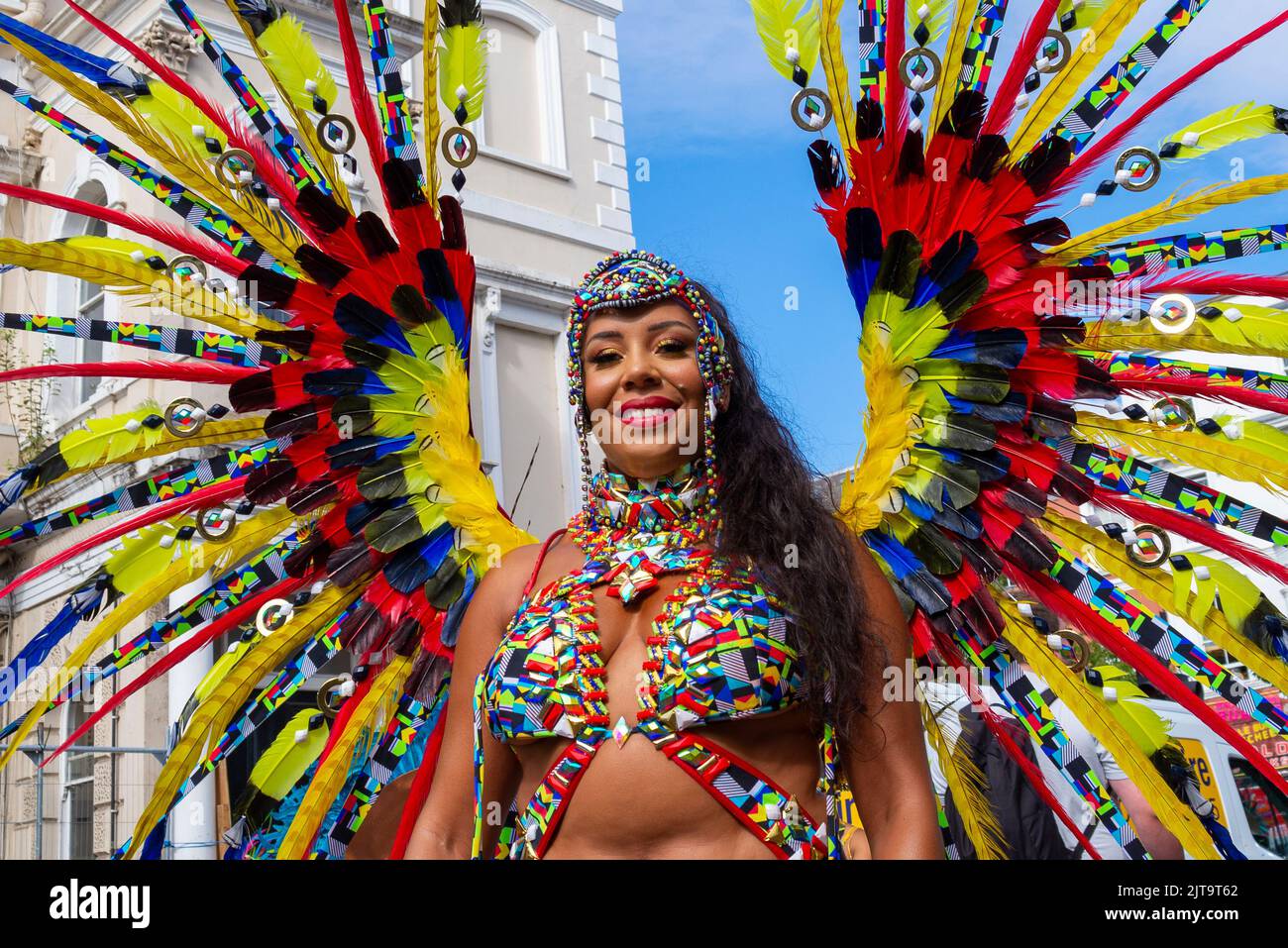 Notting Hill, Londres, Royaume-Uni. 29th août 2022. Le plus grand festival de rue d'Europe est revenu dans les rues de Notting Hill après les années annulées en raison de la pandémie de Covid. Des danseurs exotiques et des groupes musicaux sur le thème jamaïcain défileront dans les rues, avec de la nourriture et des divertissements dans la rue autour de la région, ajoutant à l'événement. Le Grand Parade a lieu le lundi des fêtes de la Banque comme point culminant du festival de trois jours qui a commencé en 1966. Les participants se rassemblent à proximité dans leurs costumes colorés. Femme en robe-tête ornée de plumes aux couleurs vives Banque D'Images