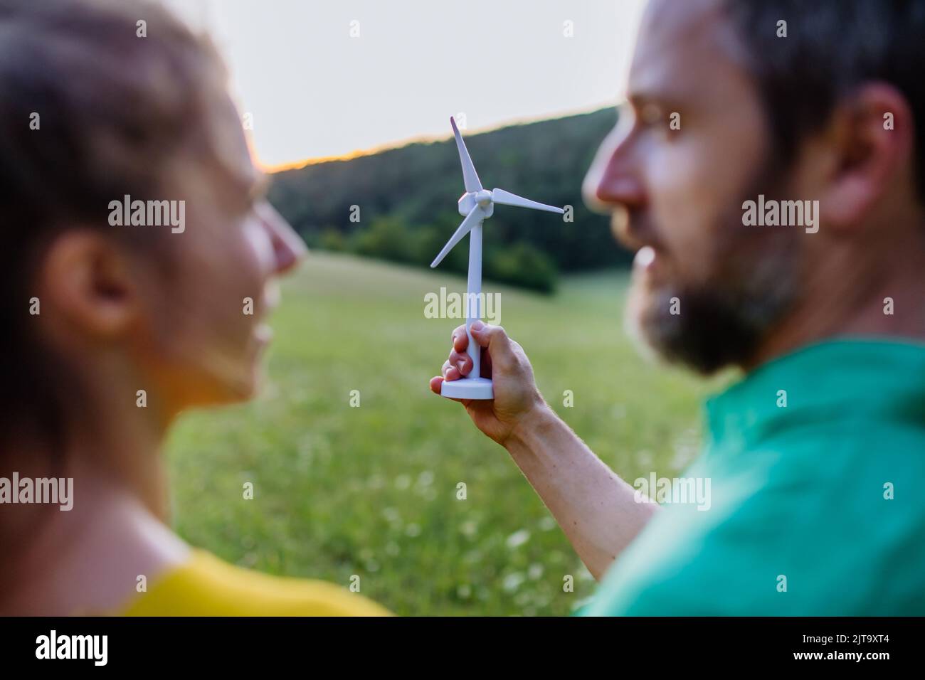 Couple debout dans la nature avec modèle d'éolienne. Concept d'écologie Ressources futures et renouvelables. Banque D'Images